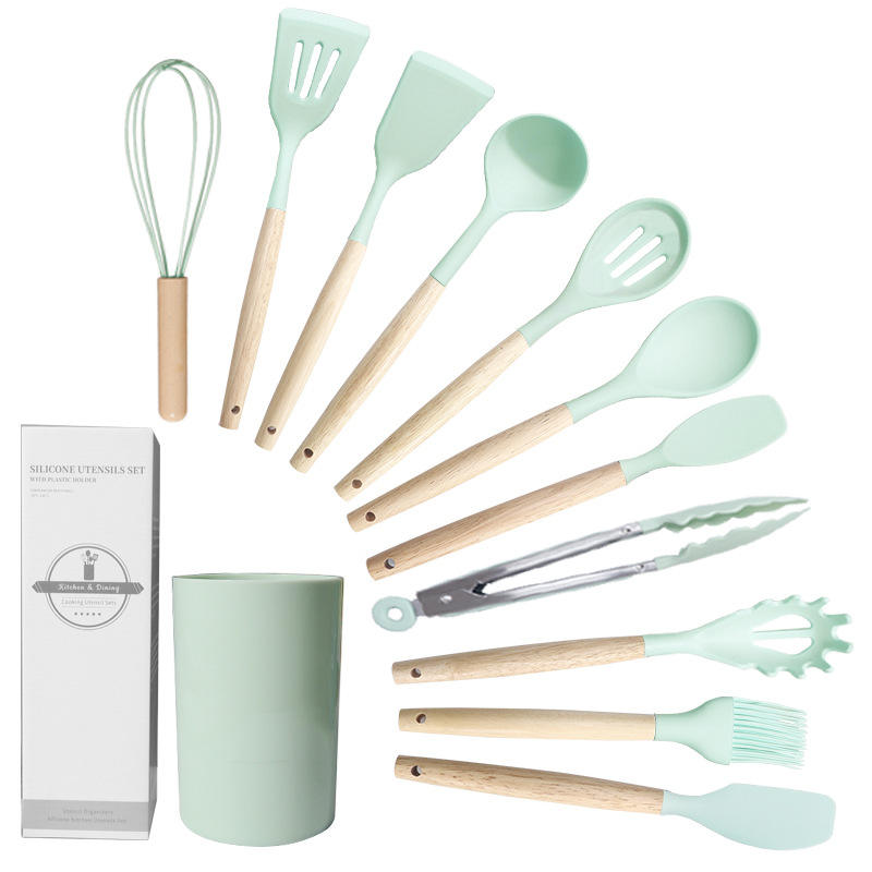 Set of kitchen utensils with mint green handles and wooden accents, including a whisk, spatulas, and tongs